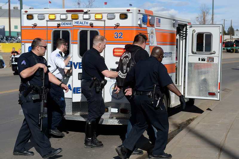 Denver Police escort a man in handcuffs away from the National Western Stock Show complex and into an ambulance January 30, 2016. DPD reported a shooting and stabbing at the complex during the Colorado Motorcycle Expo leaving one dead and several wounded. (Photo by Andy Cross/The Denver Post)